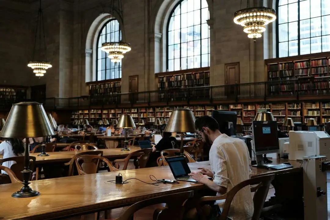 a man is sitting at a table in a library with old fashioned brick architecture